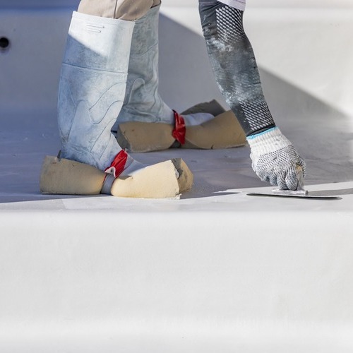 worker rolling out single-ply roofing